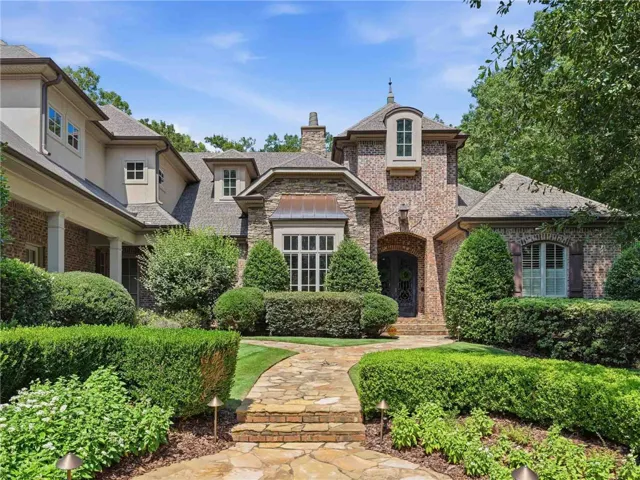 A graceful stone pathway guides you through meticulously manicured landscaping to this distinguished brick residence.
