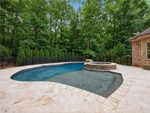 A tranquil oasis awaits, complete with a sparkling pool, integrated spa, and expansive stone patio perfect for relaxation.
