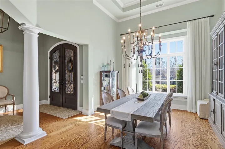 Ornate double doors welcome you into this elegant dining room featuring rich hardwood floors and an intricate chandelier.