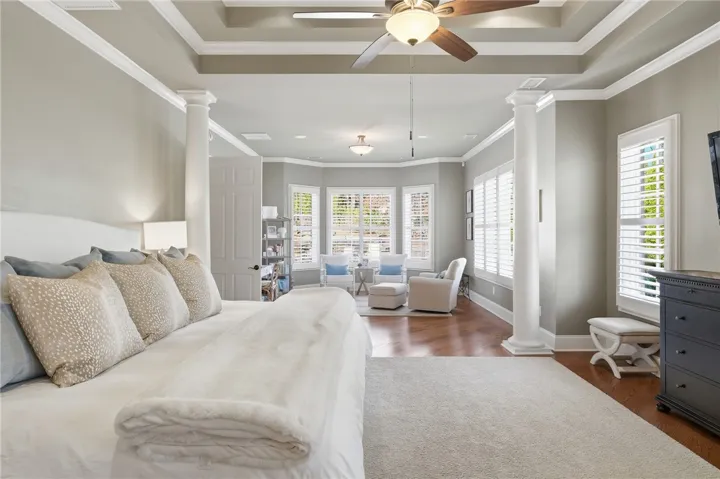 A spacious primary bedroom featuring a tray ceiling, recessed lighting, and a charming bay window seating area.