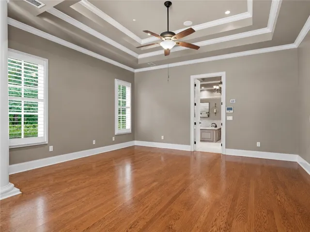 Rich hardwood floors complement tray ceilings in this generously proportioned sleeping area.