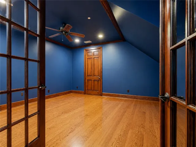 An inviting private office features rich hardwood flooring and distinctive architectural elements, including a slanted ceiling and exposed wooden beams.