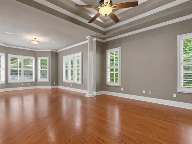 Rich hardwood floors complement elegant tray ceilings in this versatile living space.