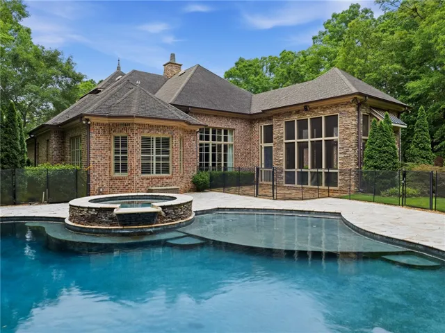 An inviting in-ground pool and stone-accented spa provide outdoor relaxation next to this stately brick residence.
