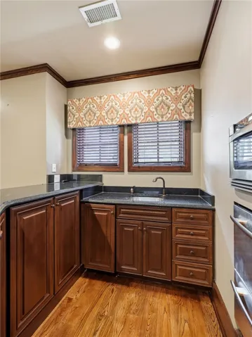 Rich hardwood floors complement custom cabinetry in this well-appointed bar area.
