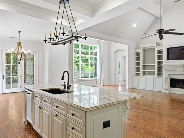 An open layout connects the kitchen to a fireside living space under soaring ceilings.
