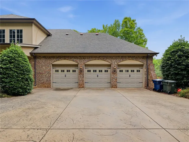 Three garage doors complement the brick and stucco exterior, offering ample vehicle storage.