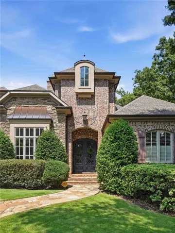 Ornate double doors and a stone pathway welcome visitors to this elegant brick exterior.