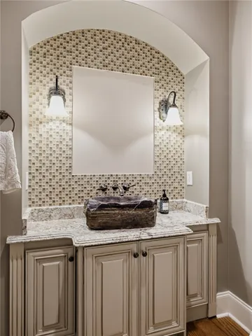 A unique, sculpted basin adds character to this well-appointed bathroom vanity with mosaic tile accents.