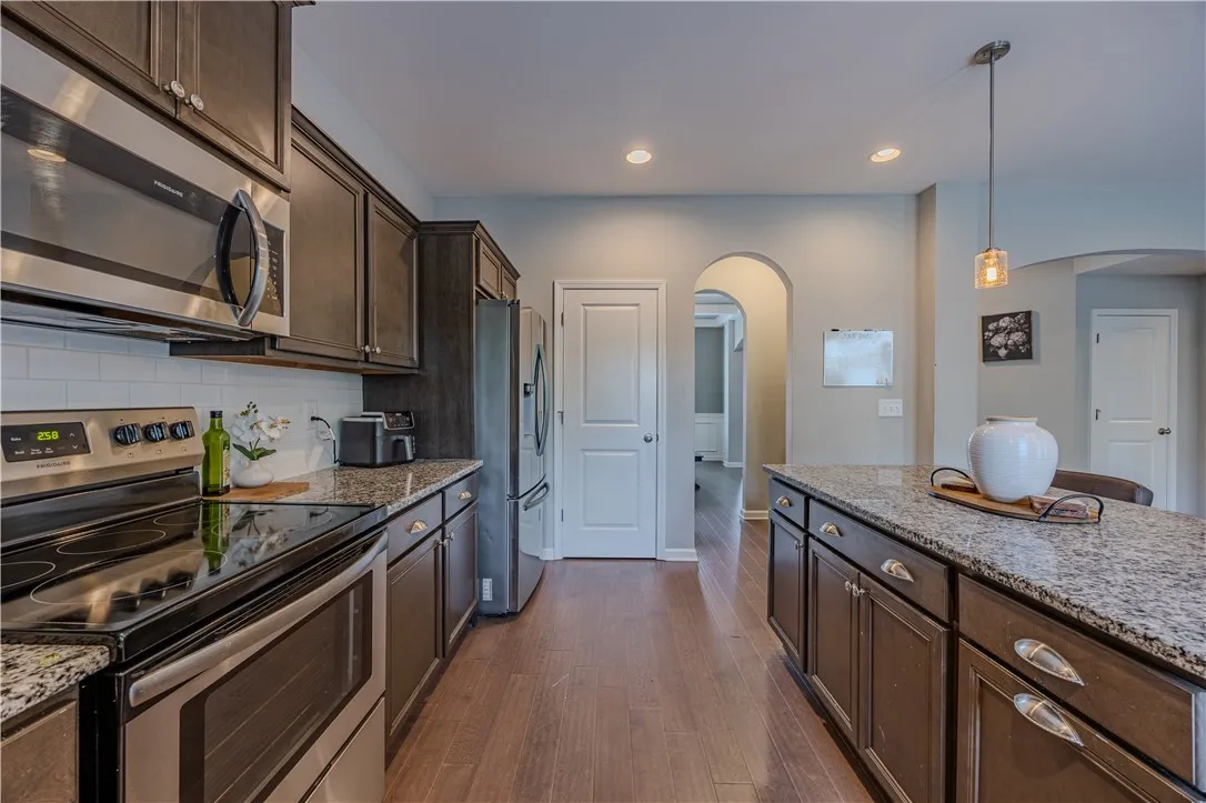 An inviting kitchen features a central island, rich cabinetry, and a full suite of stainless steel appliances.