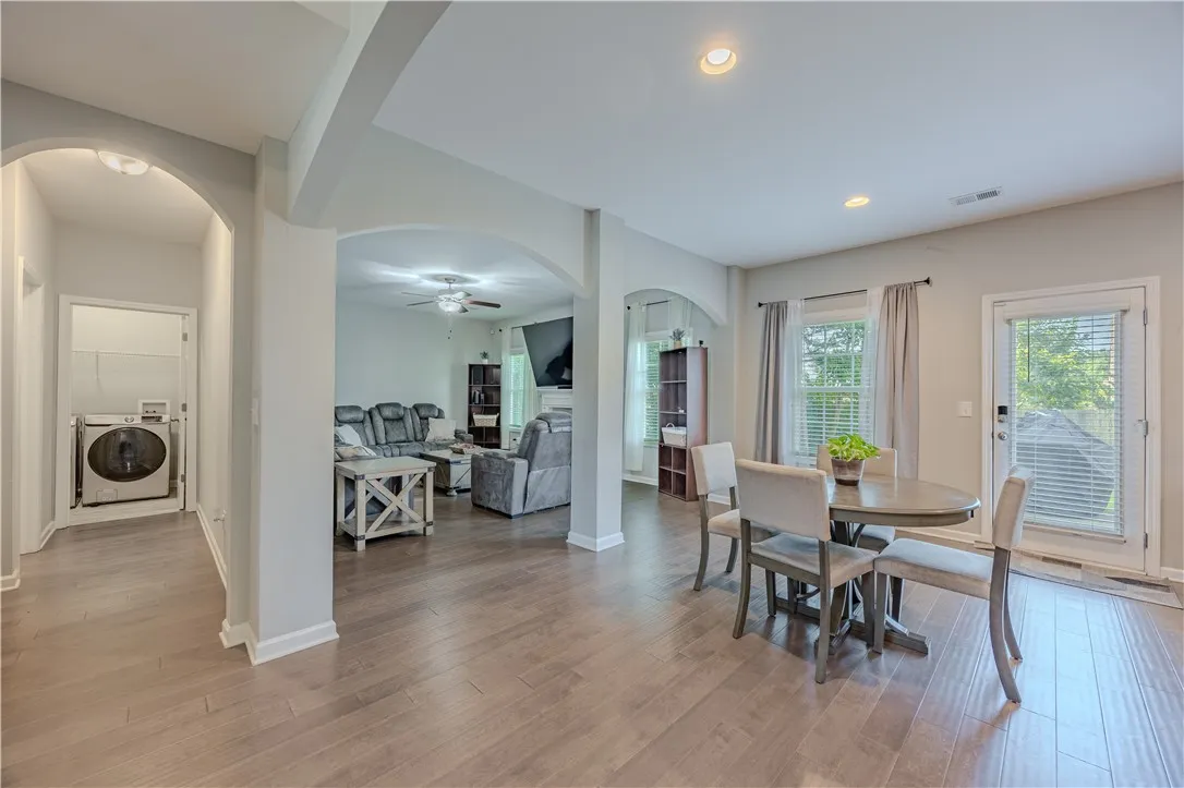 Hardwood floors stretch across this open-concept layout, connecting the dining area to the inviting living space and utility room.