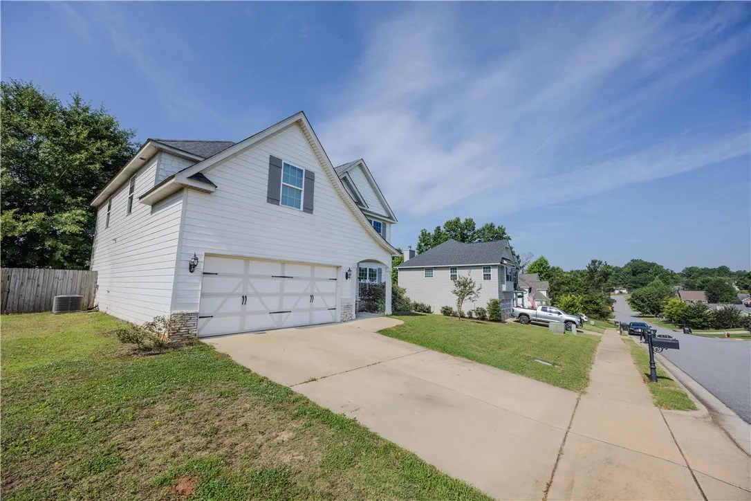 A classic white home boasts an attached garage with a wide driveway and neatly manicured front lawn.