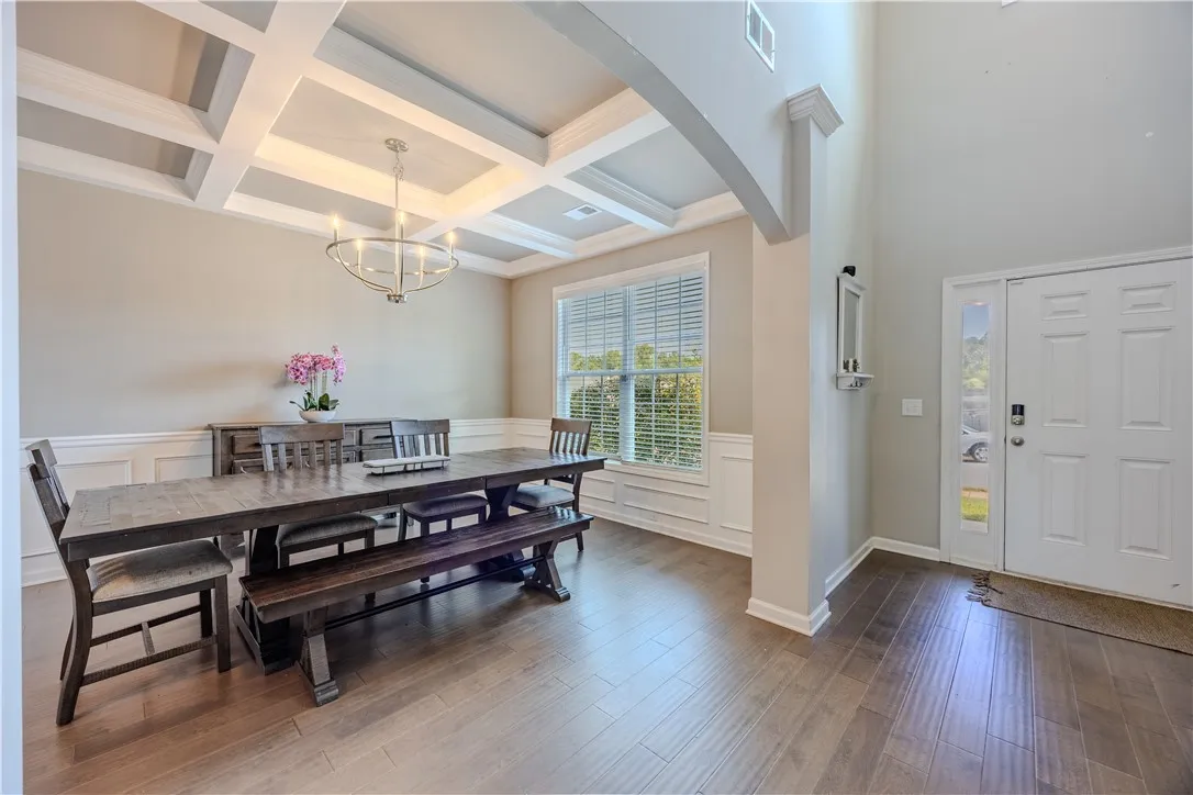 A welcoming dining space featuring rich hardwood flooring and an elegant coffered ceiling.