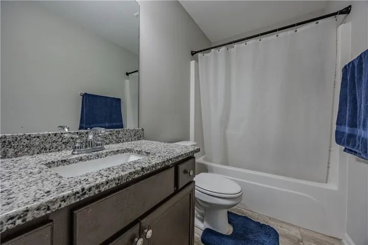 Granite counters and a clean white tub-shower combo complete this functional bathroom.
