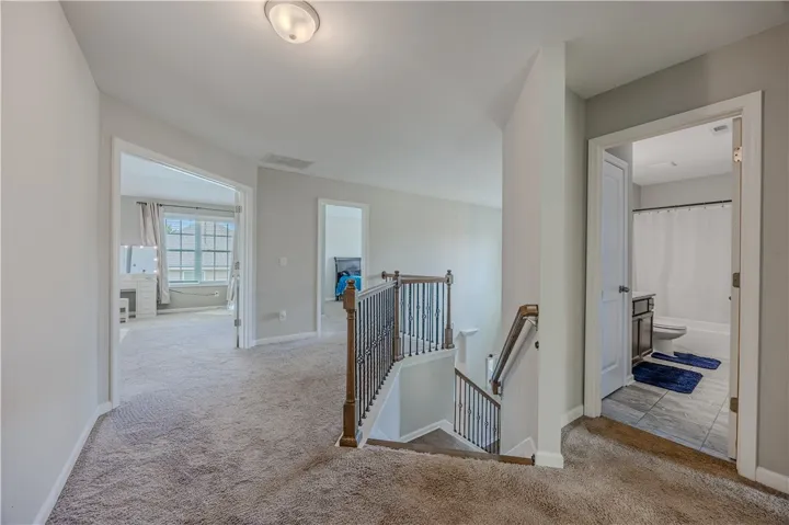 A well-lit landing provides access to various rooms, including a bedroom with a large window.