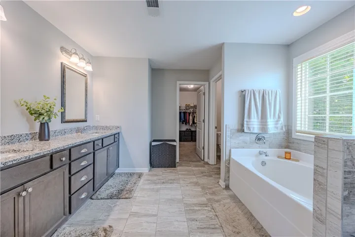 Luxurious bathing retreat features a deep soaking tub and a spacious dual-sink vanity with granite countertops.