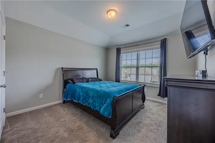 Comfortable bedroom with plush carpeting and a tray ceiling, ideal for serene relaxation.