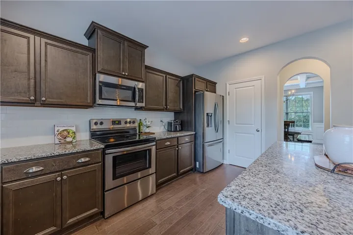 A well-appointed kitchen features dark wood cabinetry, stainless steel appliances, and sleek granite countertops.