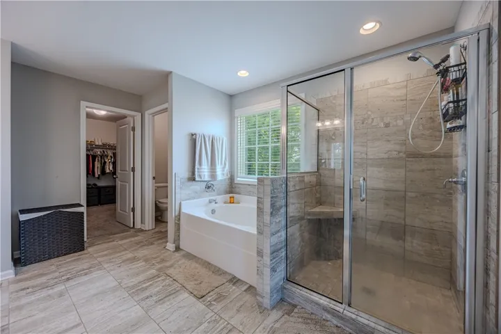 A corner soaking tub and glass-enclosed shower create a tranquil bathing retreat.