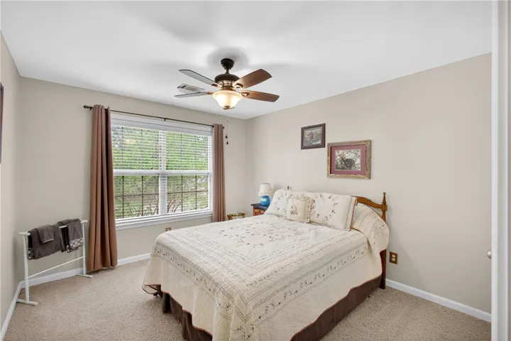 A well-lit 2nd story bedroom features plush carpeting and a large window offering natural views.
