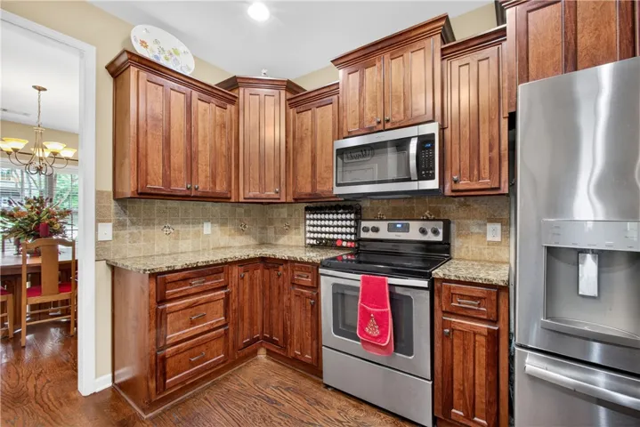 A corner kitchen showcases rich wood cabinetry, granite countertops, and stainless steel appliances.