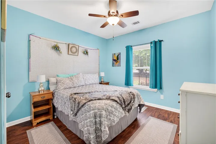An additional 1st floor guest bedroom features rich wood flooring, a window providing natural light, and a convenient ceiling fan.