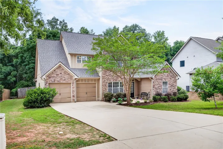 A well-maintained facade showcasing stone and siding accents, complemented by a broad concrete driveway.
