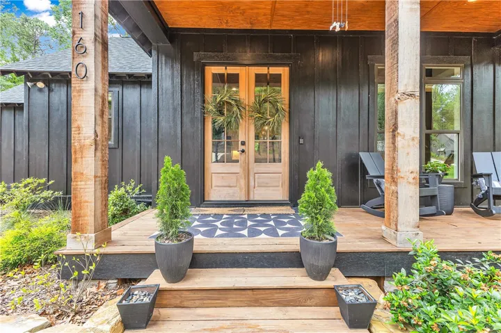 A welcoming wooden porch extends from this charming black-clad residence.