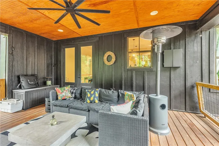 An inviting outdoor living space features dark-stained walls, a warm wood plank ceiling, and natural wood flooring.