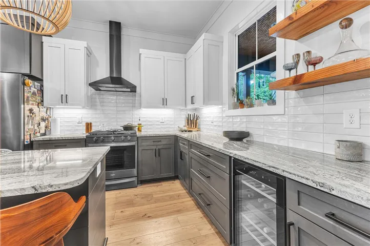 An inviting kitchen features light hardwood floors and a mix of white and gray cabinetry, complemented by a large island.