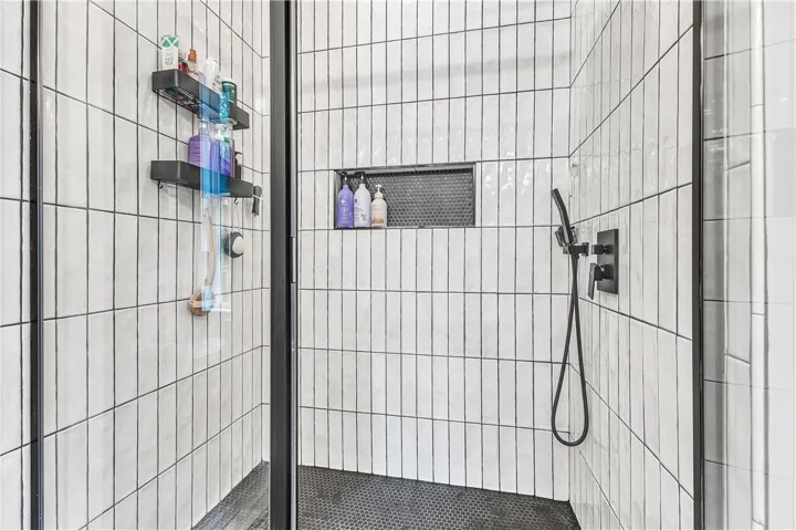 A modern shower with sleek vertical tiling and a dark hexagon-tiled floor offers a spa-like retreat.