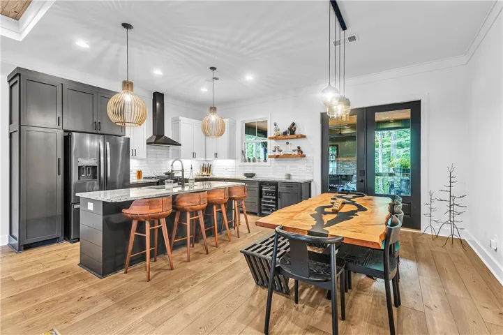 An open concept kitchen features abundant natural light, sophisticated dark cabinetry, and elegant hardwood flooring.