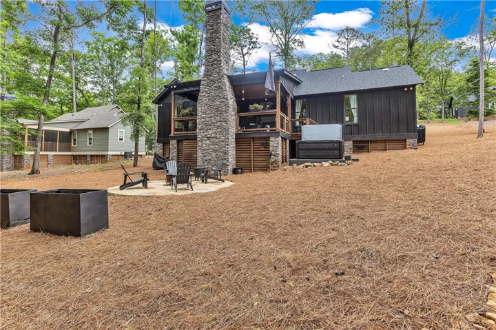 A spacious backyard with a patio, hot tub, and stone chimney offers ample outdoor living.