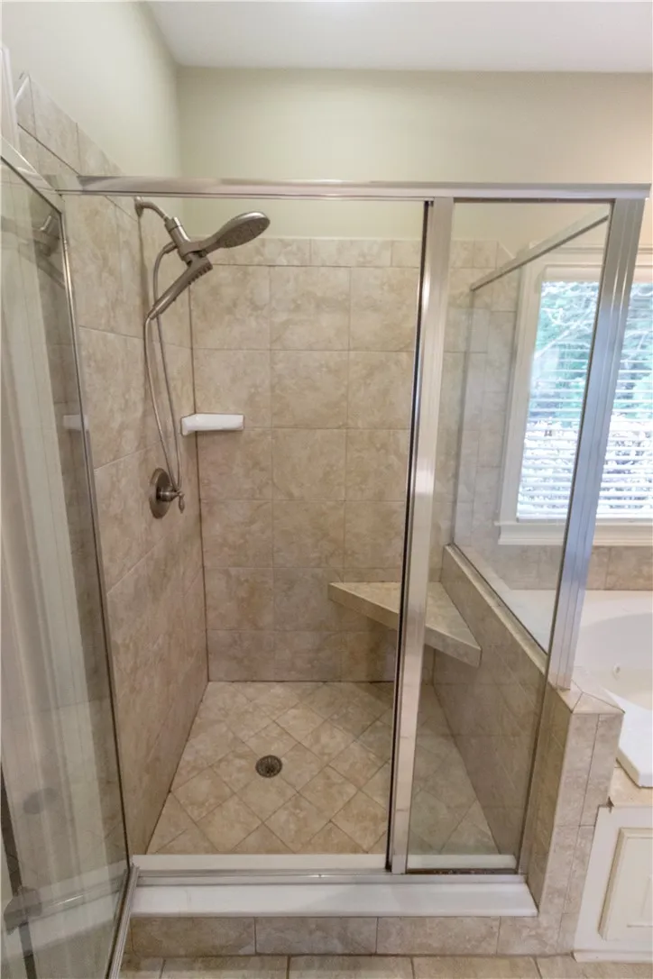 Indulge in a generously proportioned walk-in shower with integrated seating and classic tiled finishes.