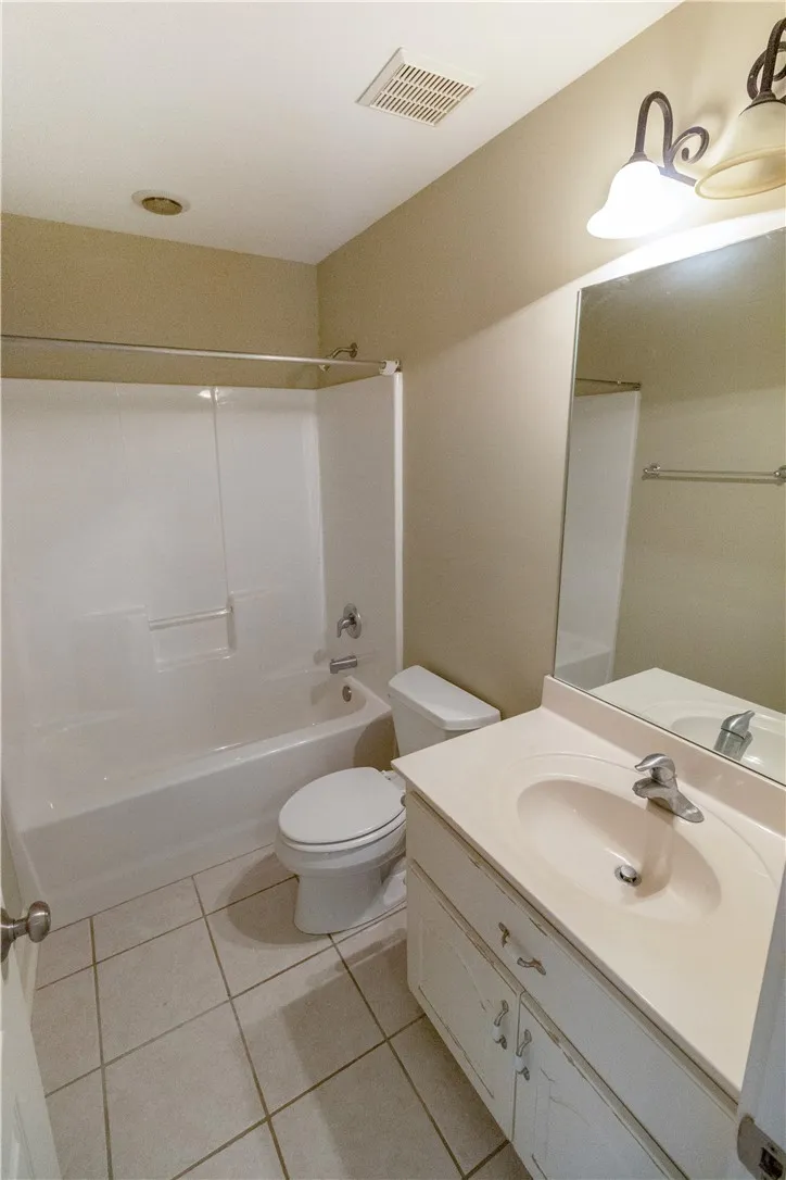 Functional full bathroom featuring a tub-shower combination, single vanity, and tiled floors.