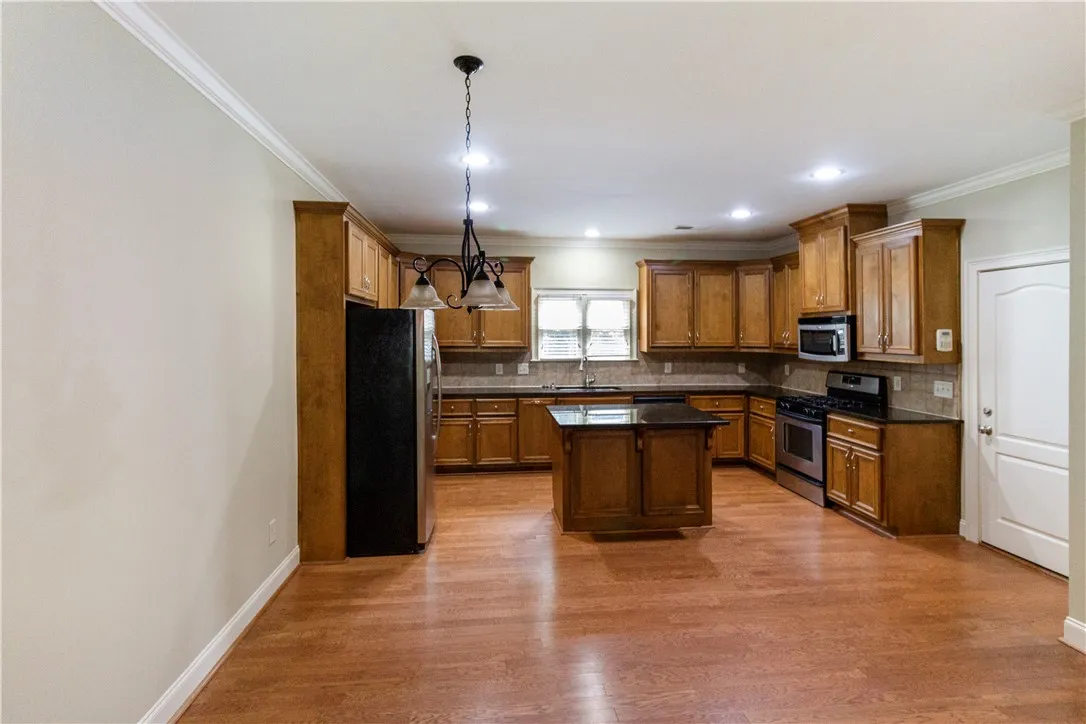 An inviting kitchen with a central island and richly toned hardwood flooring awaits culinary creativity.