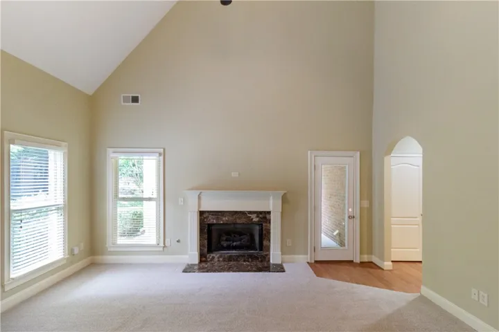 A striking fireplace with a marble surround anchors this bright, vaulted living space.