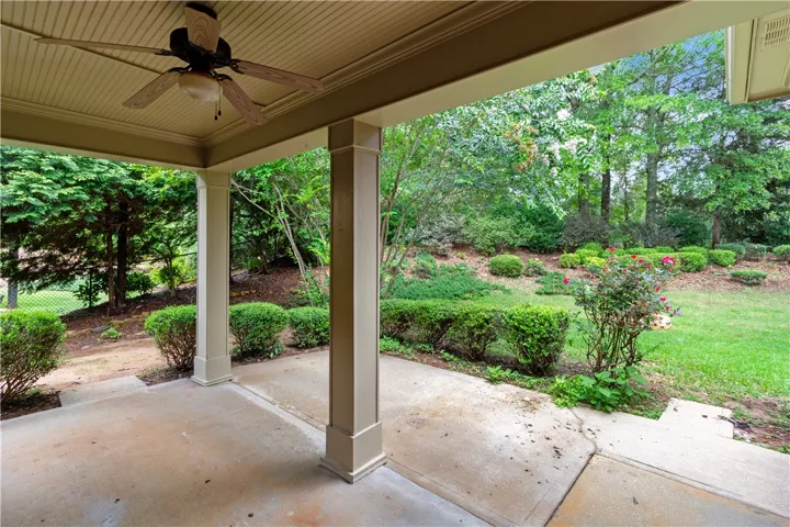 A spacious covered patio provides a serene outlook onto a verdant, well-maintained yard.