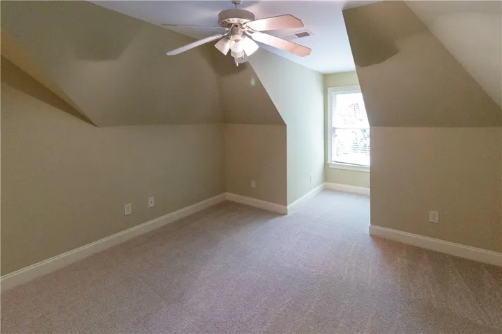 A well-lit bedroom with angled ceilings and plush carpeting.