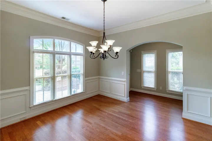 Ornate chandelier and natural light define this elegant dining space with rich hardwood floors.