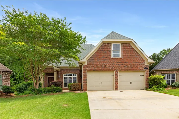 A classic brick facade welcomes residents, featuring an attached garage and well-maintained landscaping.
