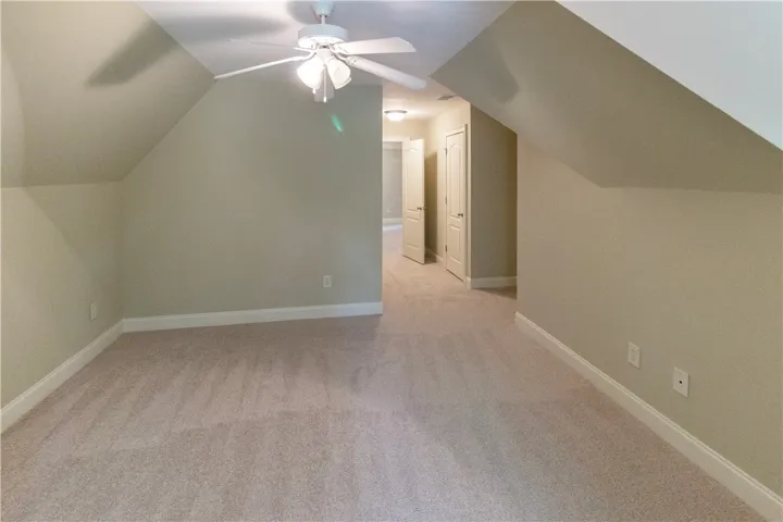A spacious bonus room features soft carpeting and sloped ceilings, offering versatile space for recreation or rest.