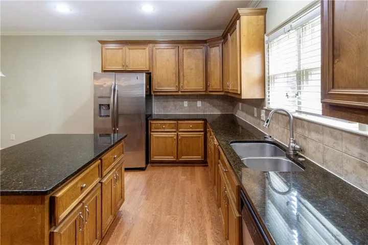 A functional kitchen boasts granite countertops, ample wood cabinetry, and sleek stainless steel appliances.