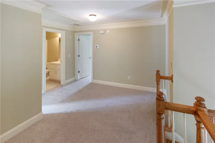 A well-lit landing features soft carpeting and white trim, leading to various rooms and a staircase.