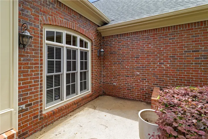 A classic brick exterior with arched window detailing and lush, vibrant landscaping creates a welcoming facade.