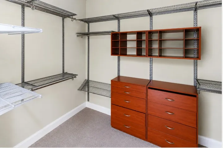 Streamlined closet system with wire shelving and rich wooden drawer units maximizes storage potential.