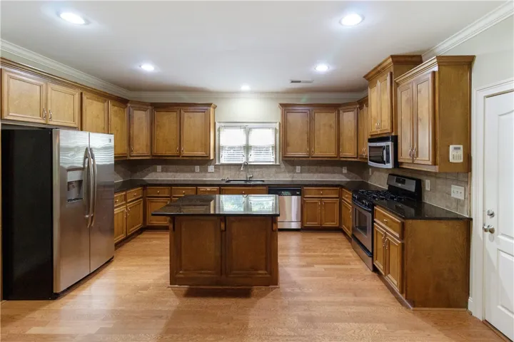 A well-appointed kitchen features rich wood cabinetry, sleek stainless steel appliances, and gleaming hardwood floors.