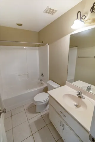 Functional full bathroom featuring a tub-shower combination, single vanity, and tiled floors.