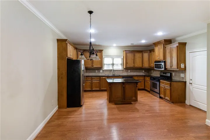 An inviting kitchen with a central island and richly toned hardwood flooring awaits culinary creativity.