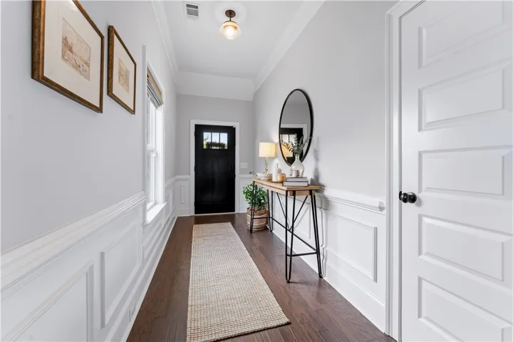 A welcoming entry features wainscoting and rich hardwood flooring, guiding guests into the home's inviting interior.